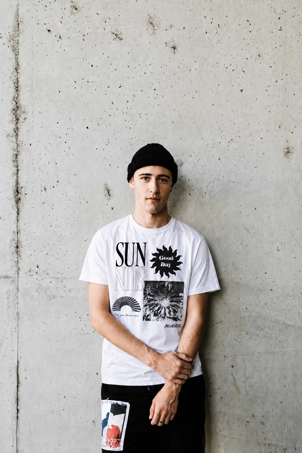 Male model wearing white SUN graphic T-shirt with contemporary black artwork print